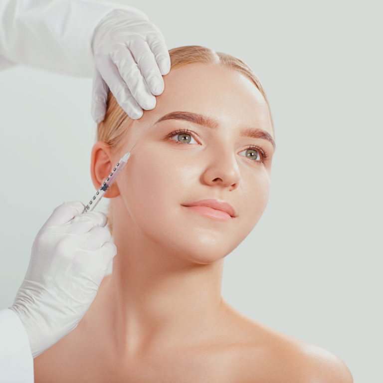Žena dostává injekci kyseliny hyaluronové do oblasti spánku od lékaře v rukavicích.